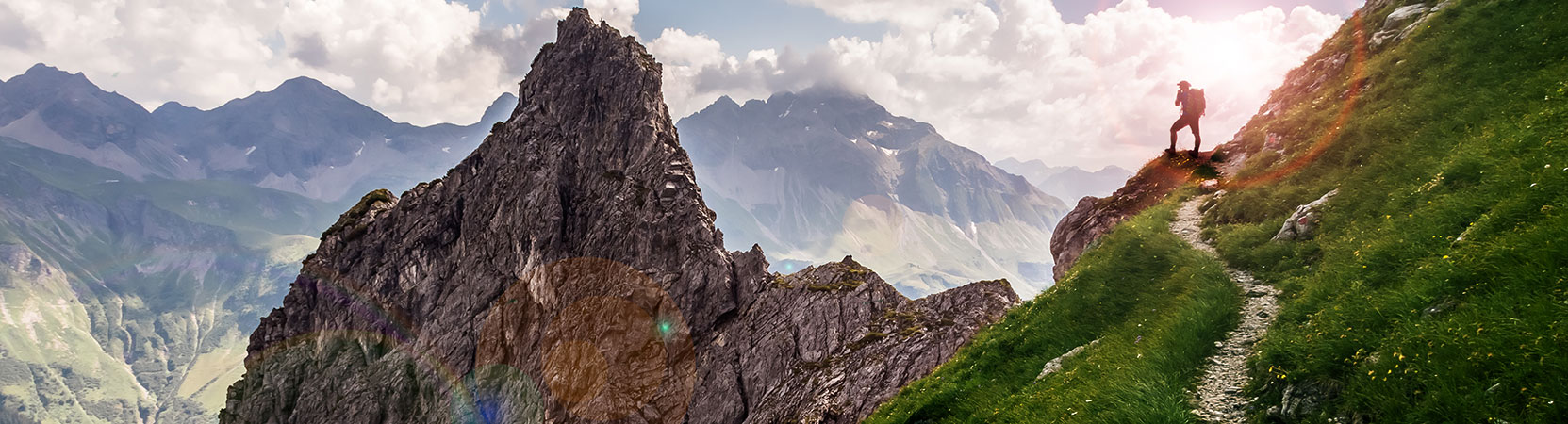 Person standing on a trail and overlooking scenic view of mountains
