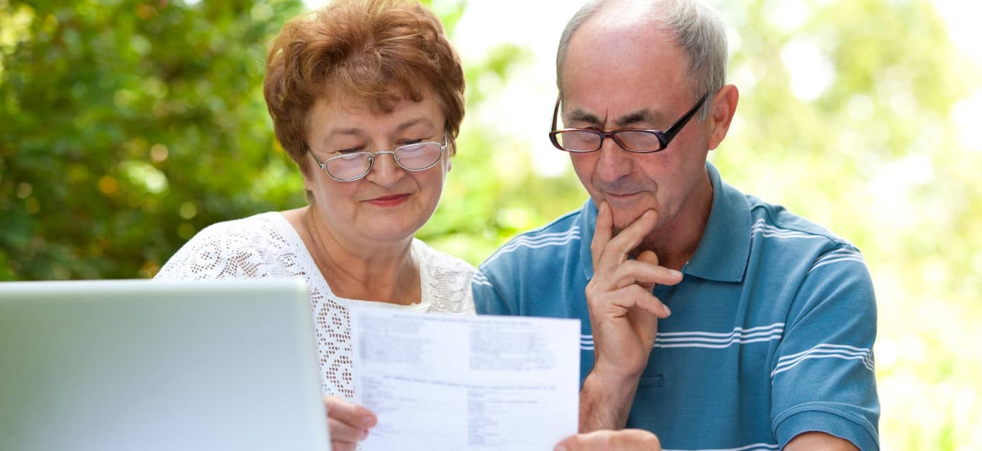 Older couple sitting with computer and social security papers