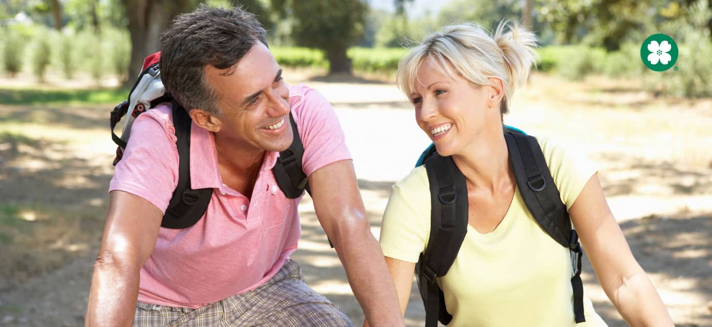 preretirement couple wearing backpacks and biking