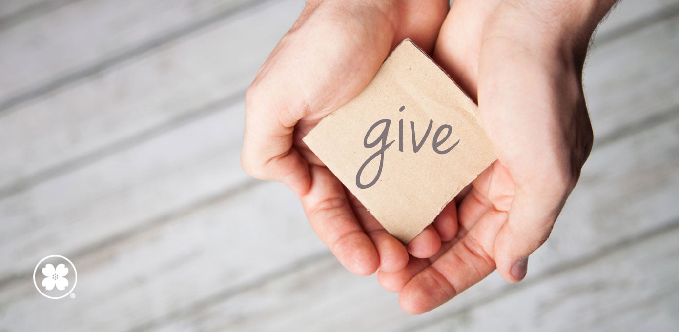 Pair of hands holding out cardboard that says "give"