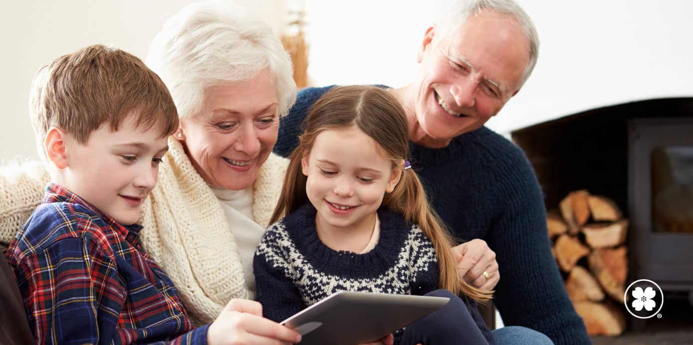 grandparents enjoying time with grandchildren watching tablet