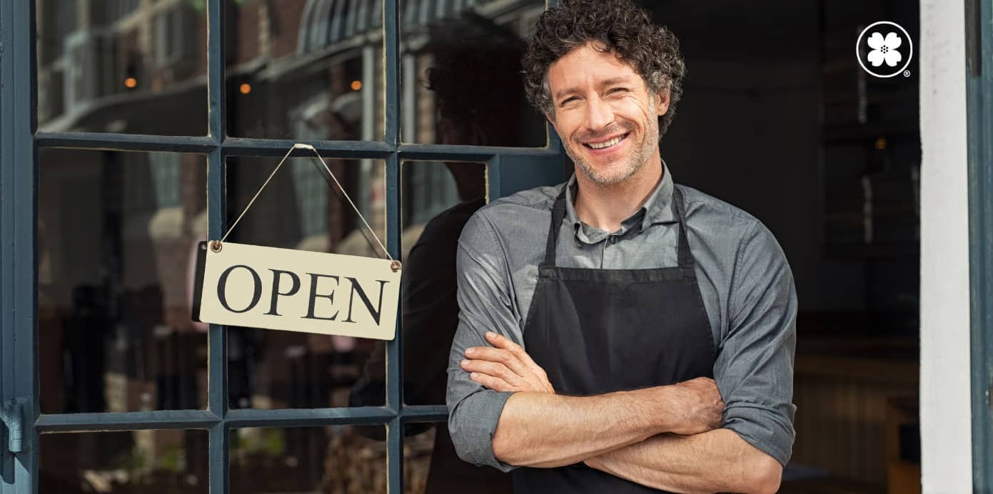 business owner standing outside shop with open sign