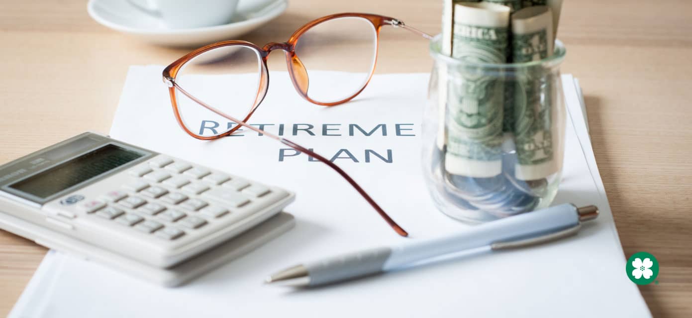 Glasses, jar with money, and calculator sitting on paper which reads retirement plan