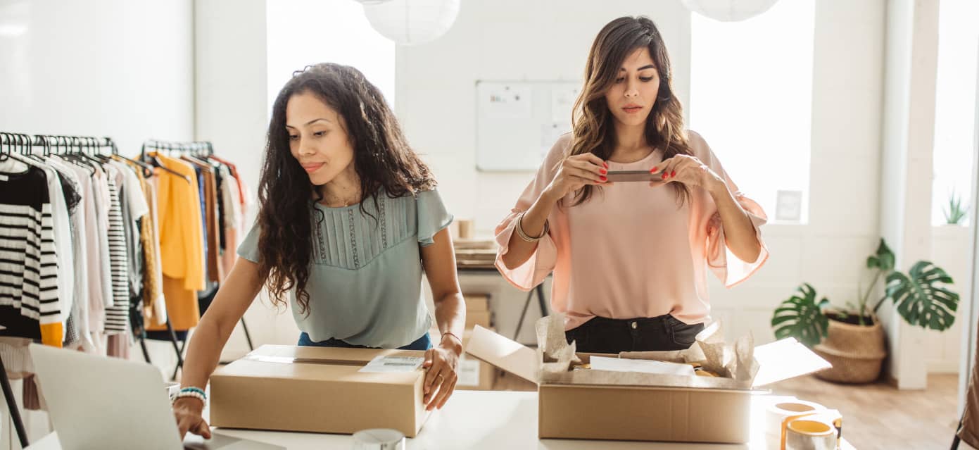 Two women packaging merchandise in their clothing store